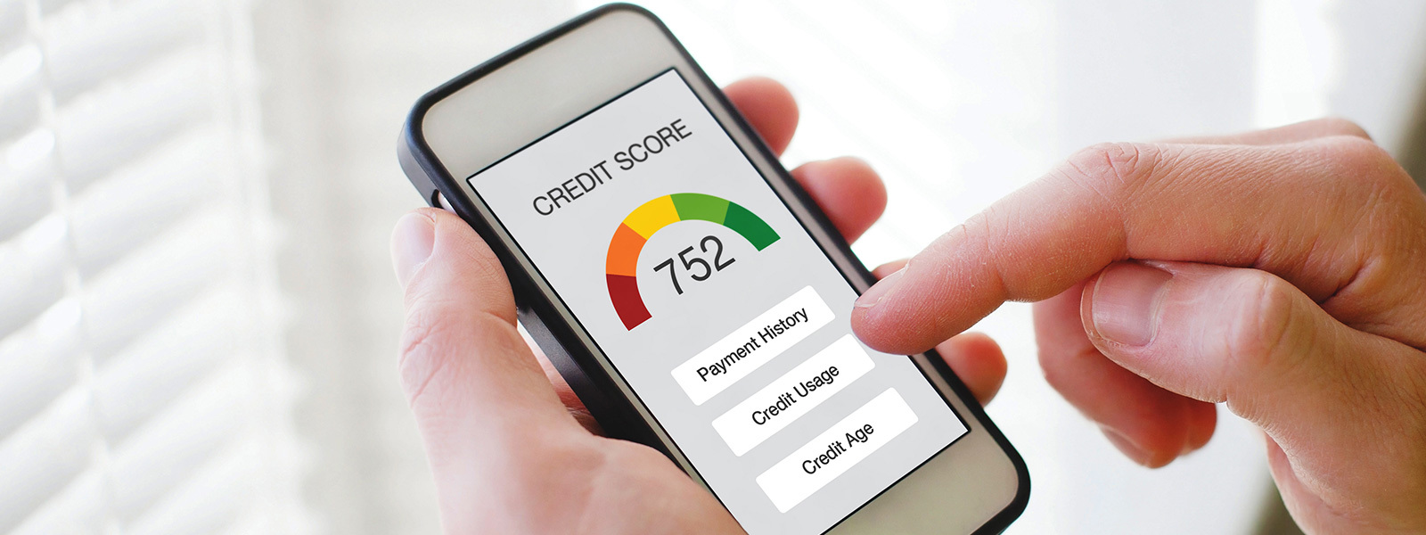 Man’s hand holding a smartphone showing a credit score as he checks to see if a soft credit check affected his credit score.