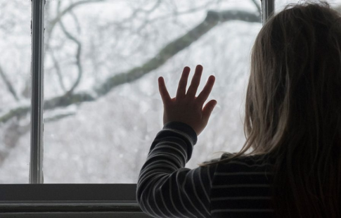 Girl looking out a window on snow-covered trees