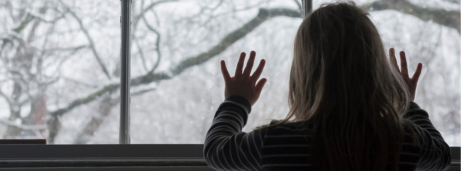 Girl looking out a window on snow-covered trees