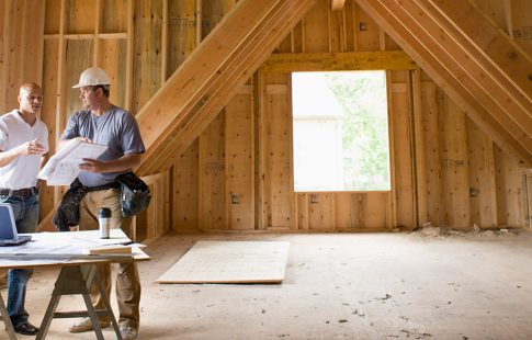 Two contractors talking in an unfinished attic