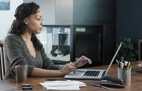 Woman using a laptop at a kitchen table