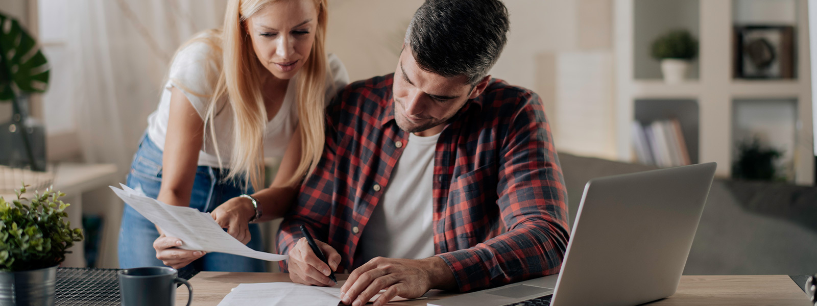 Man and woman looking at paperwork by a laptop, discussing reasons for a rejected home offer