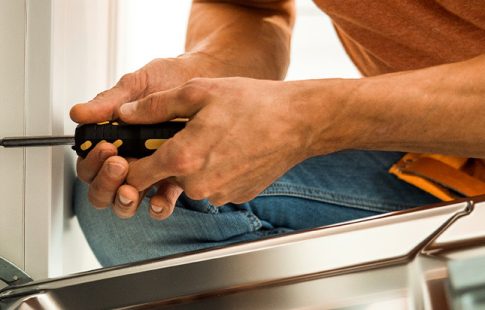 Man tightening a screw on an open dishwasher