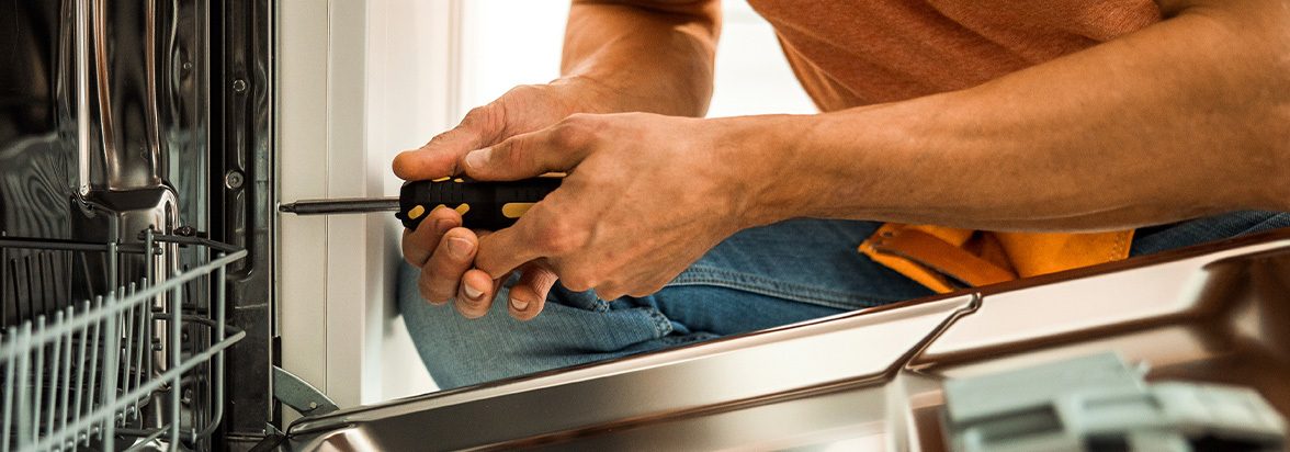 Man tightening a screw on an open dishwasher