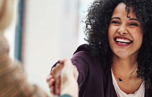 Smiling woman shaking hands with another woman after getting a mortgage with a new job