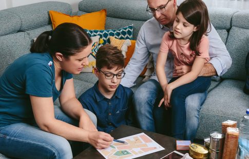 Family sitting in a living room with natural disaster supplies