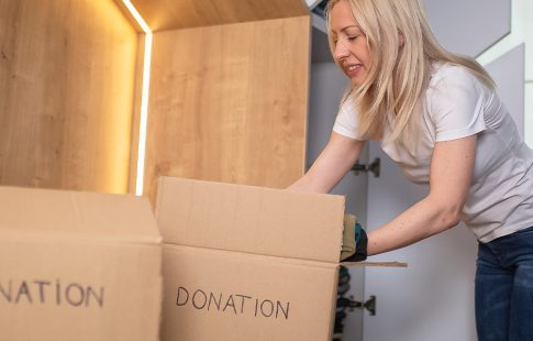 Woman putting clothes into a box marked "donation"