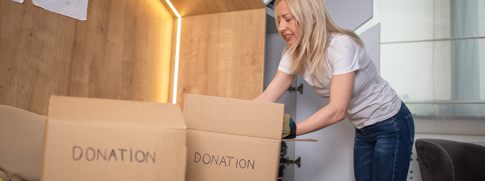 Woman putting clothes into a box marked "donation"