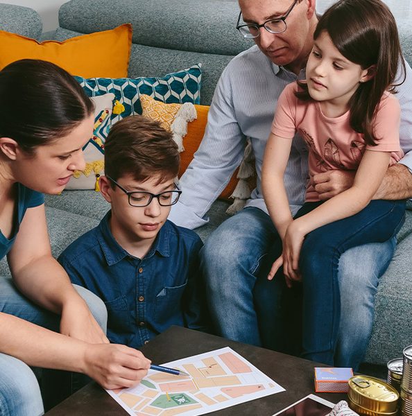 Family sitting in a living room with natural disaster supplies