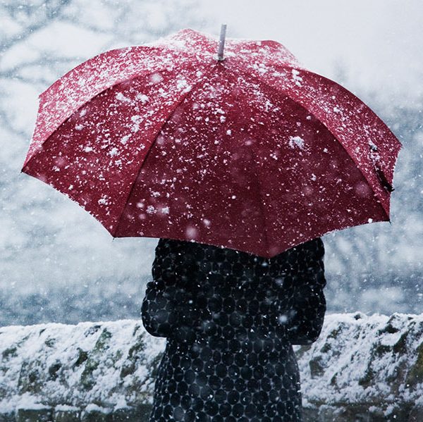 Woman walking with an umbrella in a snowstorm