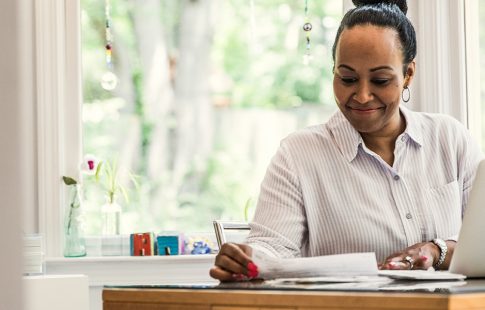 Women working at a kitchen table with a laptop and year-end mortgage tax paperwork