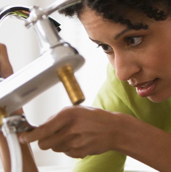 Woman fixing a kitchen faucet