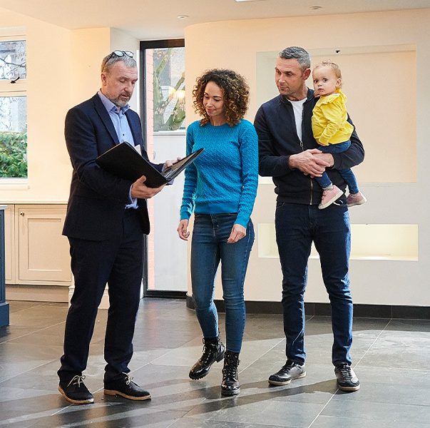 Real estate agent talking to a couple with a child at a home showing