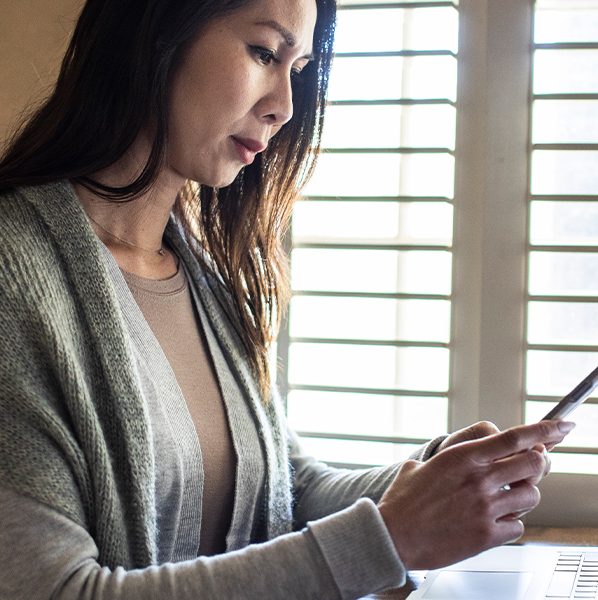 A woman with a concerned expression reads a text. Calls, texts, and emails can be quick and convenient, but they can also be a way for a mortgage scammer to steal your identity or money if your guard is down.