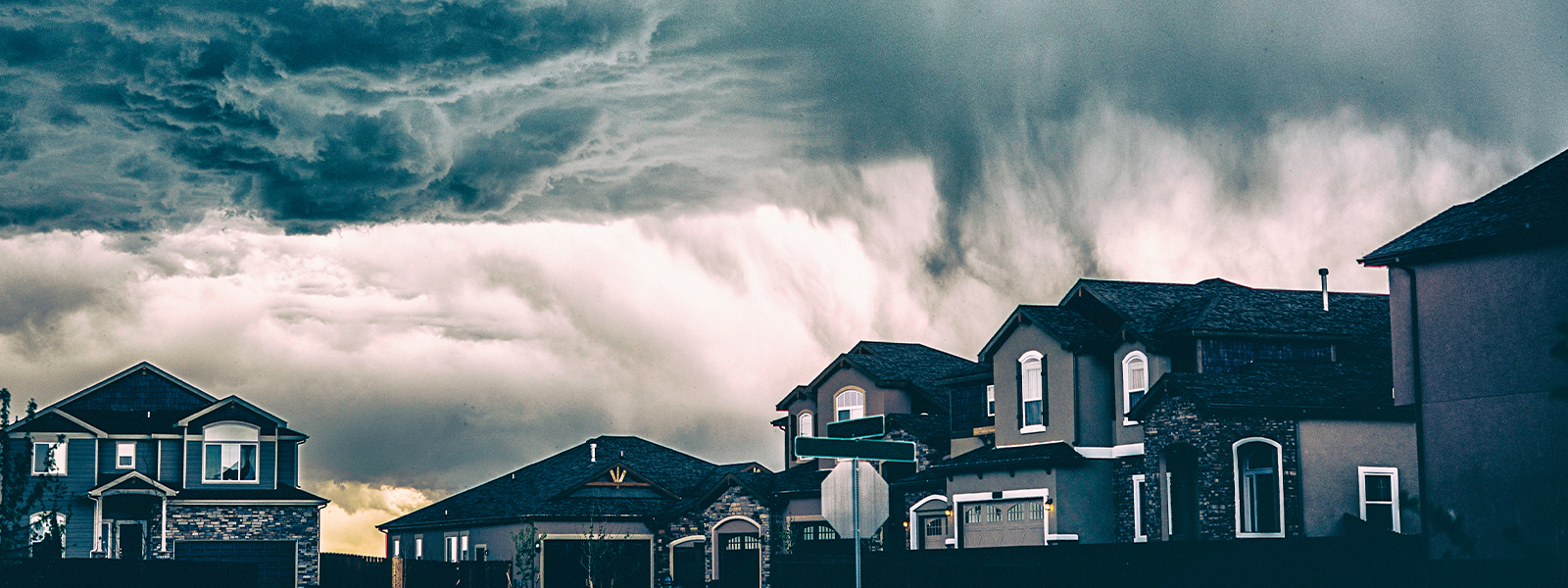 A street of houses with thick clouds building behind them