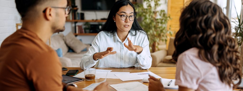 Woman sitting at a table with a couple explaining common mortgage terms