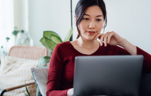 Woman wondering "Is Mr. Cooper a real mortgage company" reading an article on a laptop