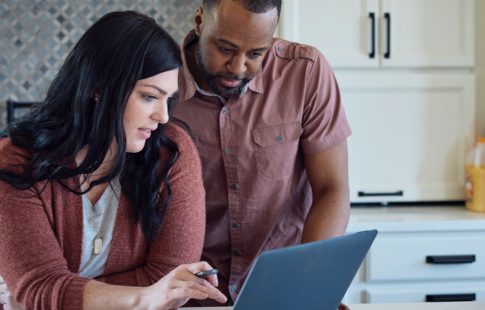 A couple looking at their laptop in the kitchen after searching for pay mortgage off early.