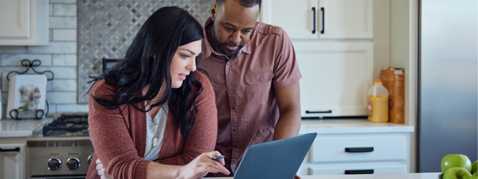 A couple looking at their laptop in the kitchen after searching for pay mortgage off early.