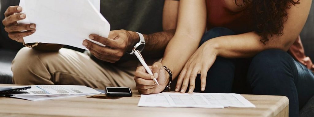 Couple works on paperwork at a coffee table while working through refinancing challenges