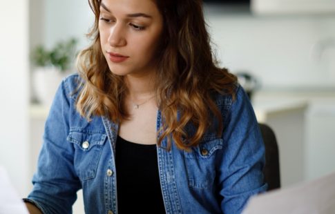 Women holding a piece of paper in each hand, deciding on a cash-out refinance vs. a home equity loan