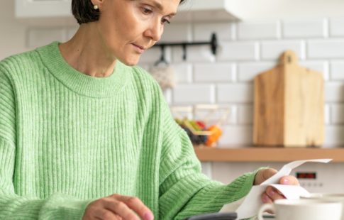 Woman in kitchen looking at receipts, wondering how to appeal a property tax assessment to save money