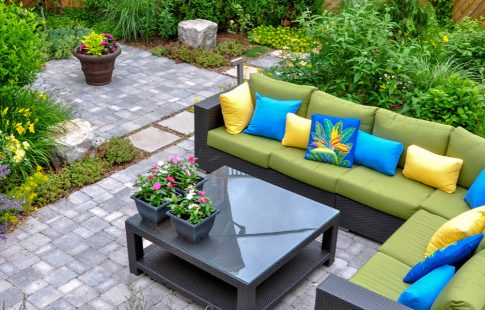 Picture of outdoor living space displaying landscaping projects to increase home value including plantings and a patio with an outdoor couch