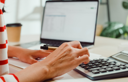 Closeup of woman's hand typing on calculator to estimate her minimum escrow balance